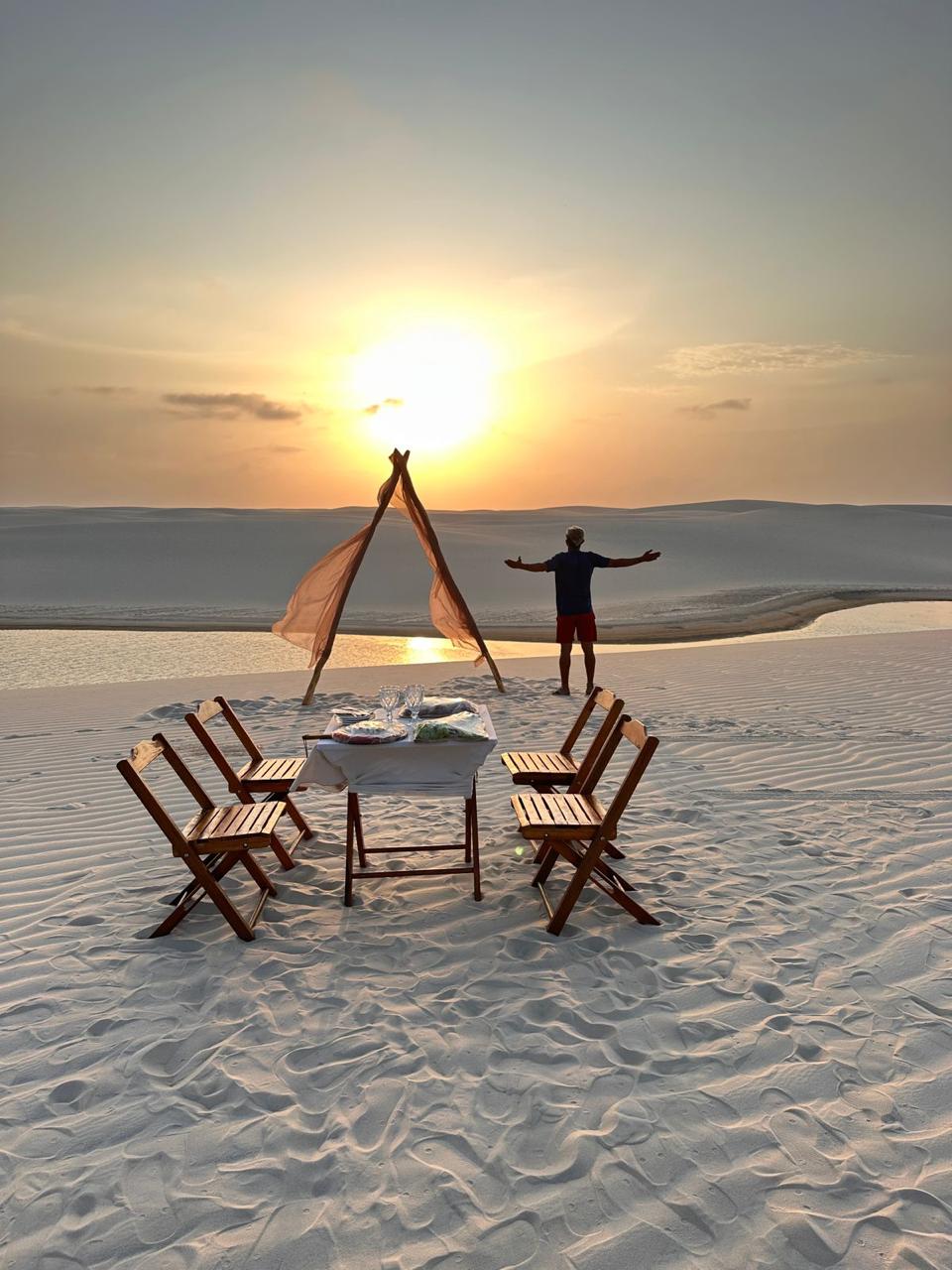 Mesa de piquenique montada no alto de uma duna ao pôr do sol